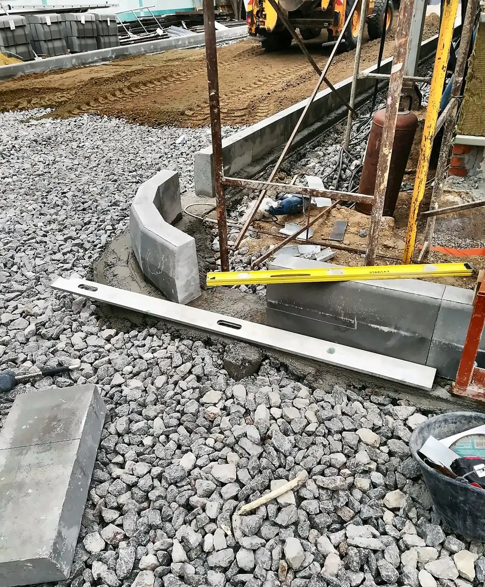 Curved kerb stones set on a compacted gravel base with a spirit level
