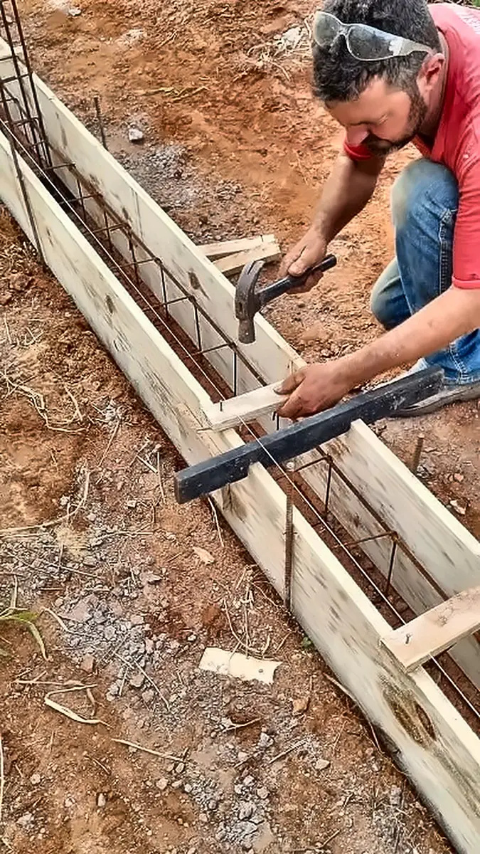 Worker fixing timber formwork and steel reinforcement on site