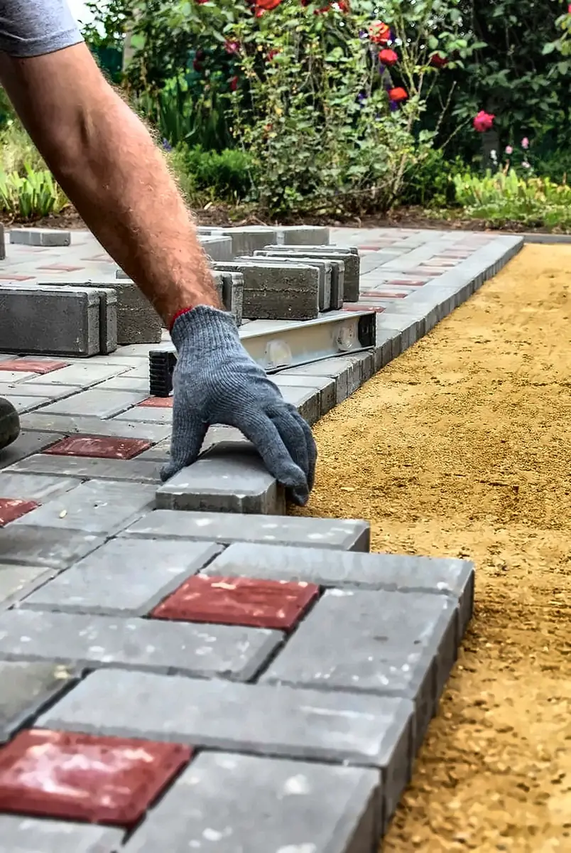 Interlocking paving blocks being laid on a levelled sand bed